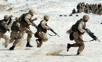 Soldiers advancing across a sandy training field